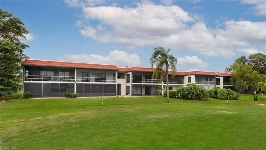 Back of house with a balcony and a lawn