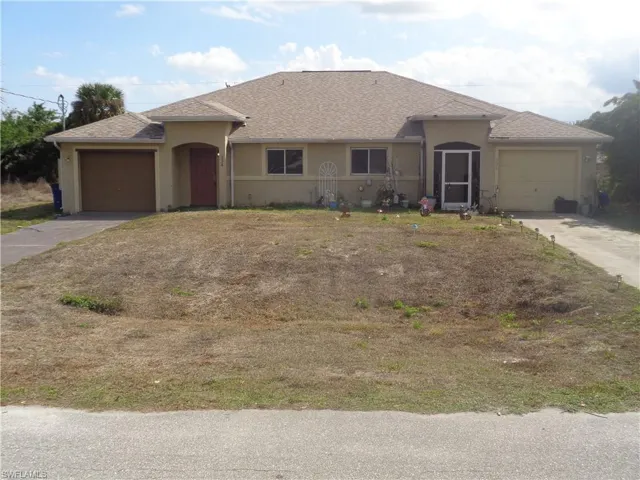 View of front of the duplex with one garage for each unit, concrete driveway, stucco siding, and a shingled roof