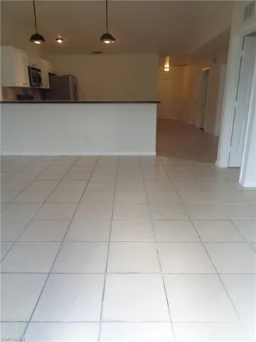 Dining area with light color tile floors. Kitchen can be seen in the back