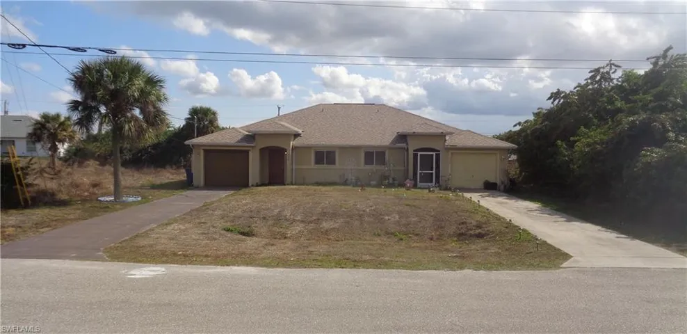 Wide angle view of the front of the duplex with an attached garage for each unit, stucco siding, and driveway