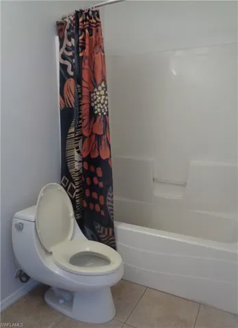 Master's bedroom's bathroom featuring   toilet and tub/shower and light patterned flooring