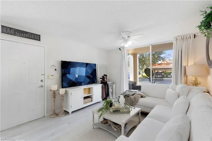 Living room with light hardwood / wood-style floors, a textured ceiling, and ceiling fan