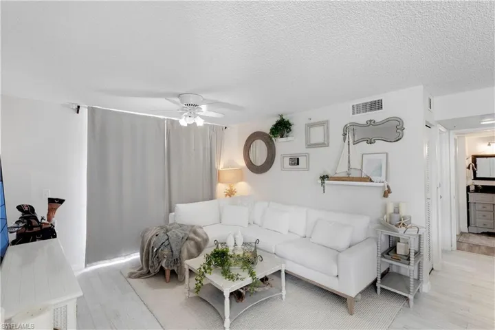 Living room with light hardwood / wood-style flooring, a textured ceiling, and ceiling fan