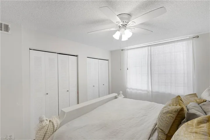 Bedroom featuring ceiling fan, multiple closets, and a textured ceiling