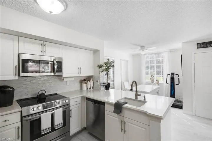 Kitchen with kitchen peninsula, sink, white cabinets, appliances with stainless steel finishes, and ceiling fan