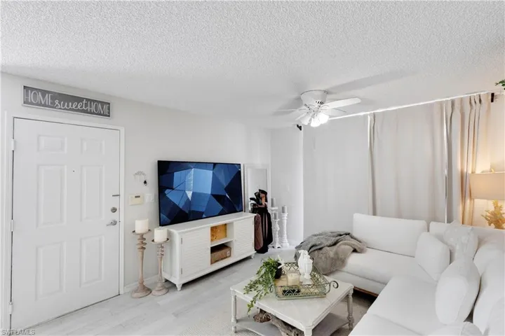 Living room with light hardwood / wood-style flooring, a textured ceiling, and ceiling fan