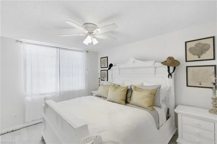Bedroom with ceiling fan, a textured ceiling, and light wood-type flooring