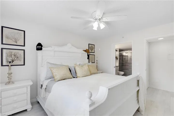 Bedroom featuring light hardwood / wood-style flooring, ceiling fan, a textured ceiling, and ensuite bath