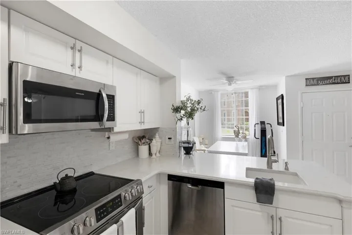 Kitchen with backsplash, appliances with stainless steel finishes, kitchen peninsula, and white cabinets