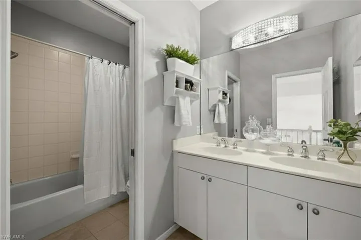Full bath featuring double vanity, shower / bath combination with curtain, and light tile patterned flooring