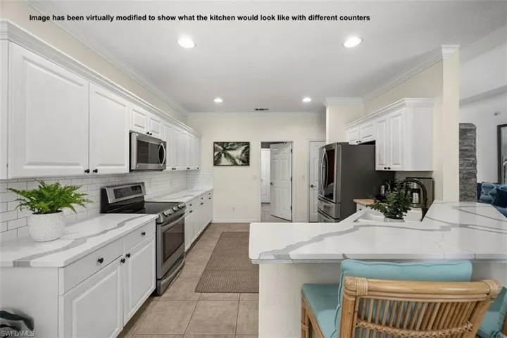 Kitchen featuring white cabinets, stainless steel appliances, light stone counters, decorative backsplash, and crown molding