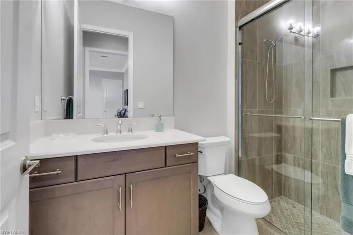 Bathroom featuring toilet, a stall shower, and vanity