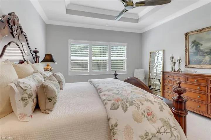 Bedroom with light carpet, a tray ceiling, a ceiling fan, and crown molding