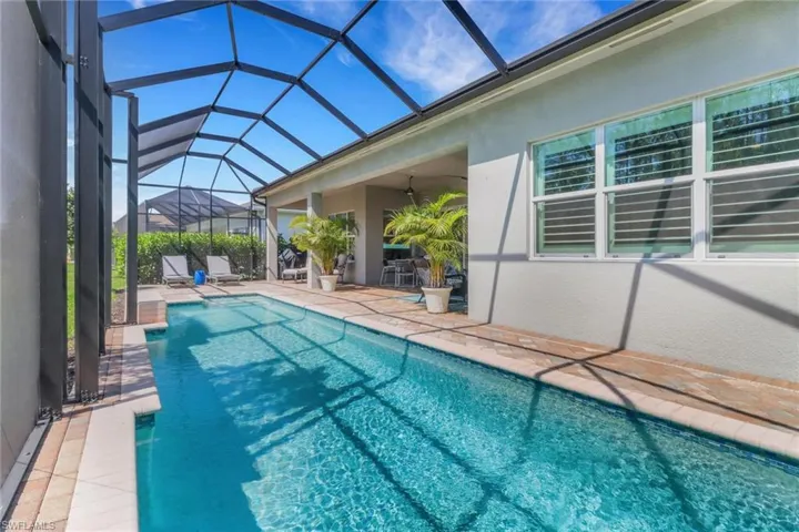 Pool featuring a ceiling fan, glass enclosure, and a patio