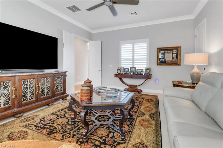 Living room with ceiling fan, ornamental molding, and visible vents