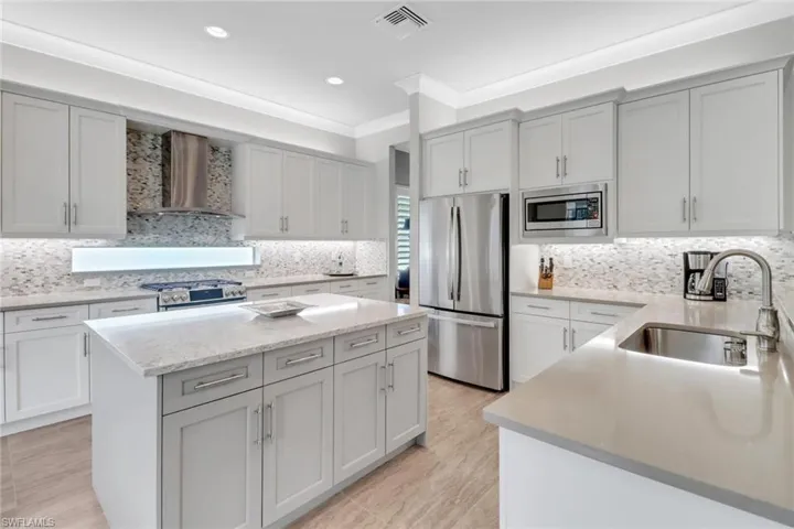 Kitchen with a kitchen island, a sink, visible vents, appliances with stainless steel finishes, and wall chimney exhaust hood