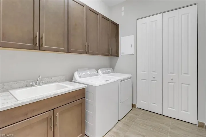 Washroom featuring washing machine and dryer, cabinet space, and a sink