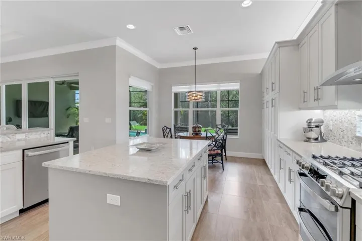 Kitchen featuring light stone counters, visible vents, appliances with stainless steel finishes, backsplash, and a center island