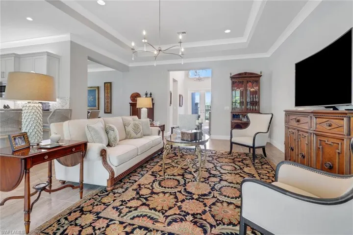 Living room with visible vents, baseboards, an inviting chandelier, a tray ceiling, and recessed lighting