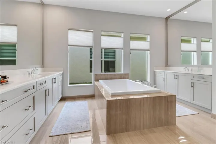 Full bathroom featuring two vanities, a sink, and a bath