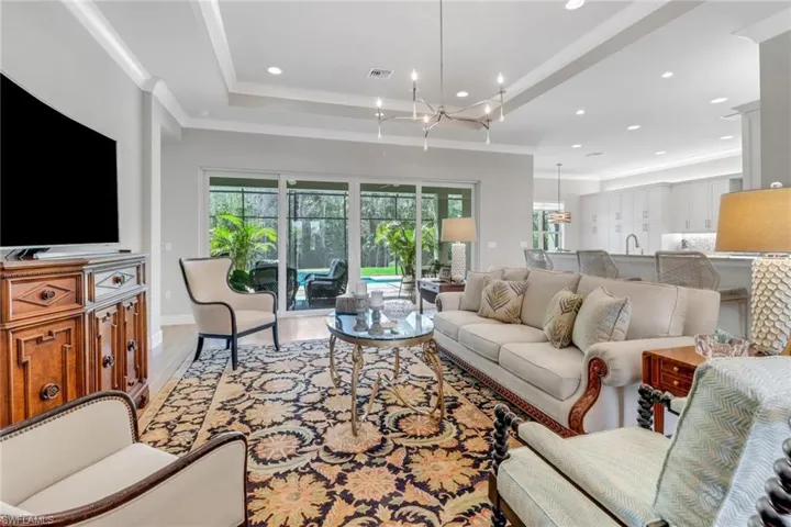 Living room with a healthy amount of sunlight, light wood-style floors, visible vents, and a tray ceiling