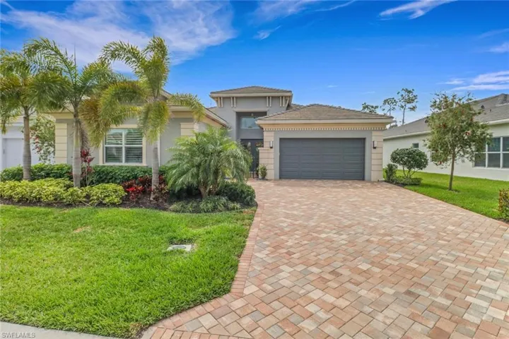 View of front of home featuring an attached garage, stucco siding, decorative driveway, and a front yard