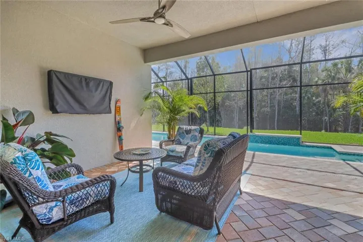 View of patio featuring ceiling fan, glass enclosure, an outdoor hangout area, and an outdoor pool