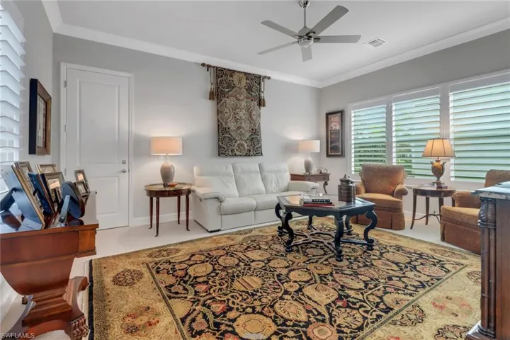 Living room featuring visible vents, ornamental molding, a ceiling fan, and baseboards