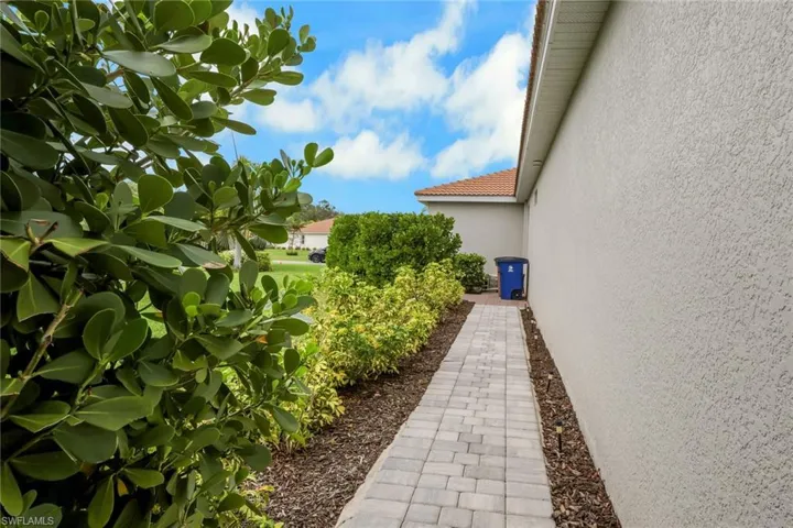 View of side property walkway to lanai with hidden trash/recycle bin storage area.