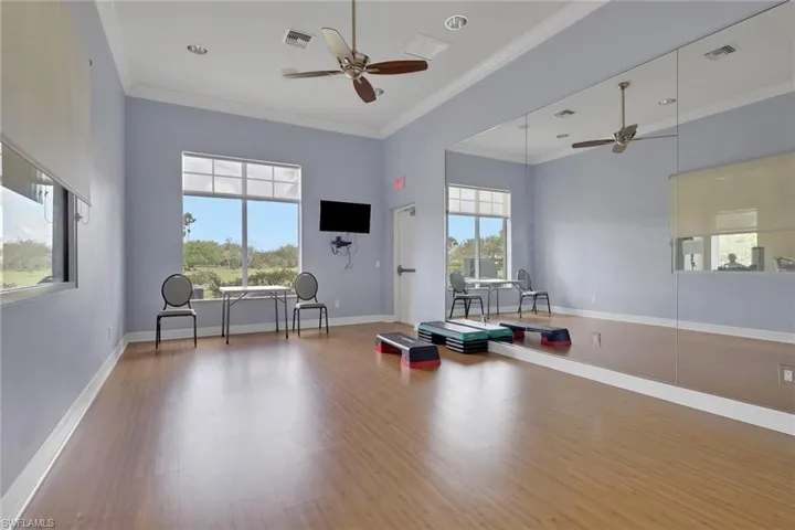 Workout room featuring crown molding, a ceiling fan, and a high ceiling