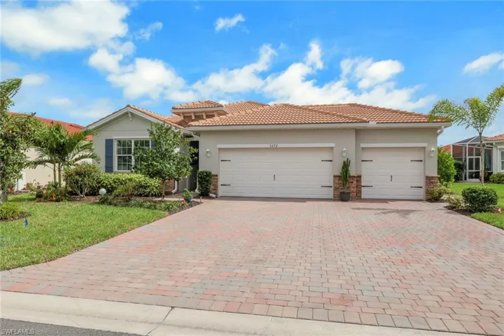 View of front with a 3 car attached garage, stucco finish with stone accents, decorative paver driveway and a tile roof.