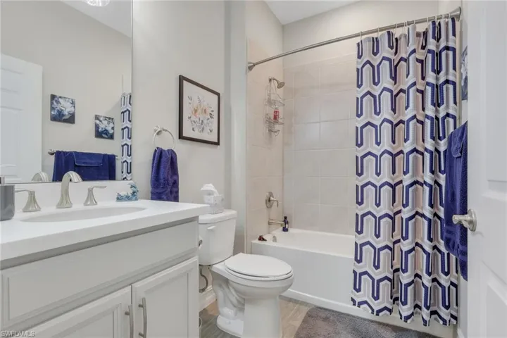Full bathroom with vanity, shower / bath combo, and tiled flooring