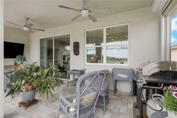 View of covered lanai, wall mounted TV and 2 ceiling fans. Covered lanai has hurricane power screens