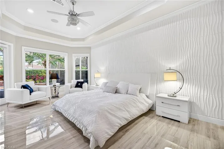 Primary Bedroom highlighting seating area , views to lanai and dimensional white accent wall.