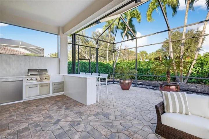View of outdoor kitchen featuring a natural gas grill and refrigerator.