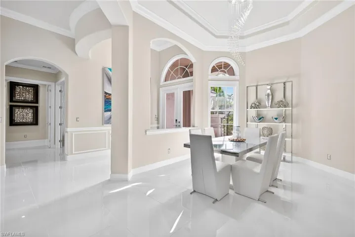 Dining space with crown molding, arched walkways, and a modern chandelier