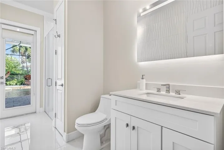 Third full bathroom with direct lanai / pool access.  Features, white vanity, quartz countertops and walk-in shower and dimensional white accent wall.