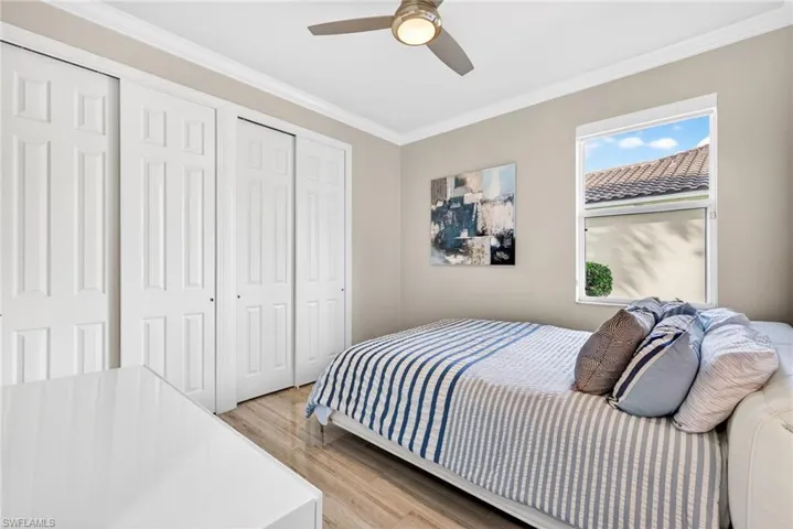 Third bedroom featuring tile plank flooring, crown molding, ceiling fan and double closets.