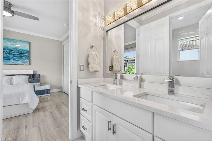 Jack and Jill bathroom with white vanity and quartz countertops.  View leading back into second bedroom.