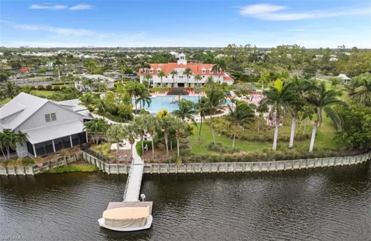 Waterfront property featuring a private dock, screened porch, swimming pool, and mature palm trees