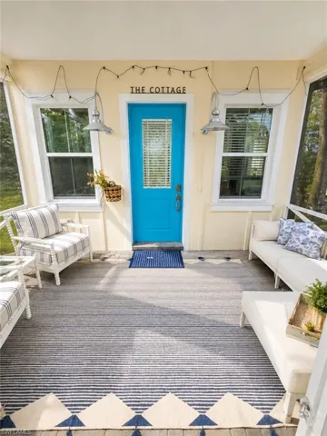 Screened porch with a vibrant blue entrance door, two windows, and overhead lighting
