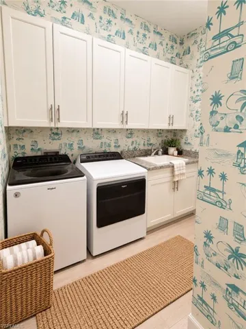 White shaker-style cabinetry with brushed nickel hardware, light-toned wood-finish flooring, a utility sink, and a stone-finish countertop