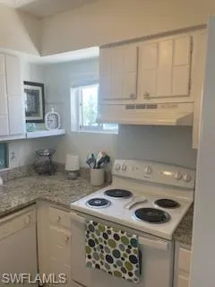 Kitchen with white range oven, white cabinets, dishwasher, and extractor fan