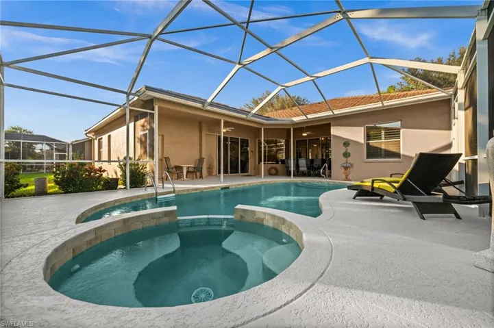 View of pool,  lanai, with connected hot tub, a patio area, and a ceiling fan