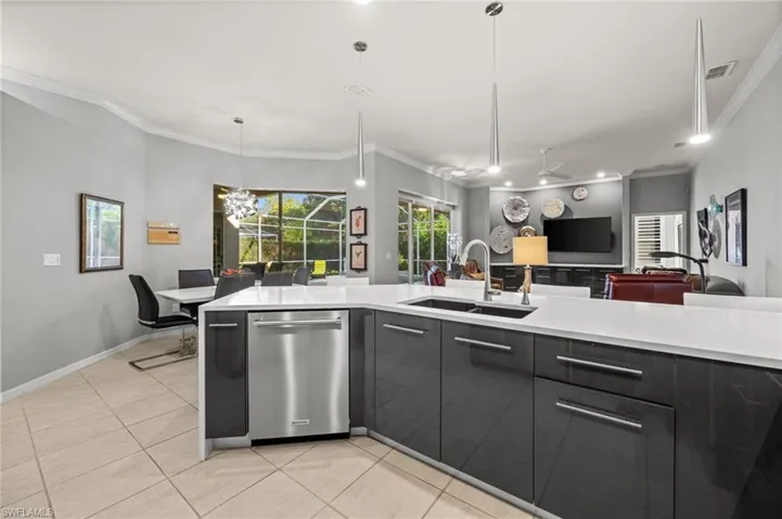 Kitchen featuring modern cabinets, dishwasher, crown molding, hanging light fixtures, and light tile patterned flooring