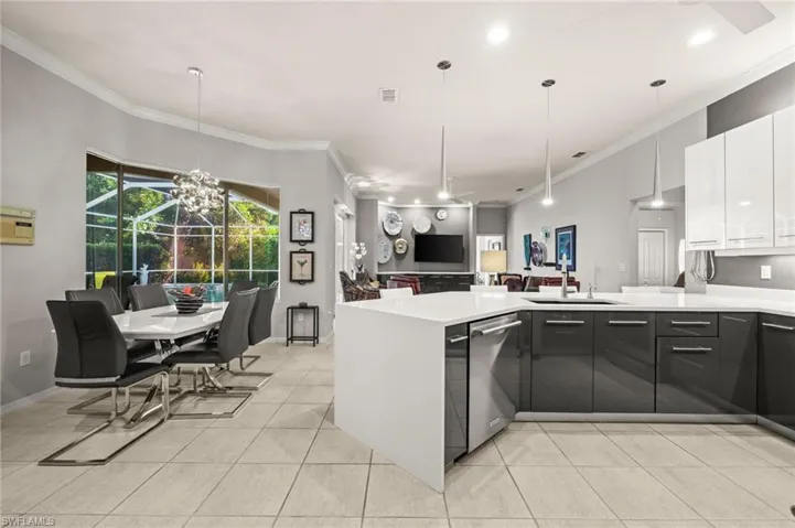 Kitchen with ornamental molding, open floor plan, a peninsula, pendant lighting, and modern cabinets
