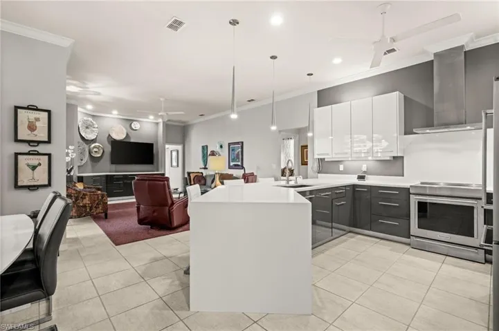 Kitchen with crown molding, ceiling fan, high end stainless steel range oven, a peninsula, and light tile patterned floors