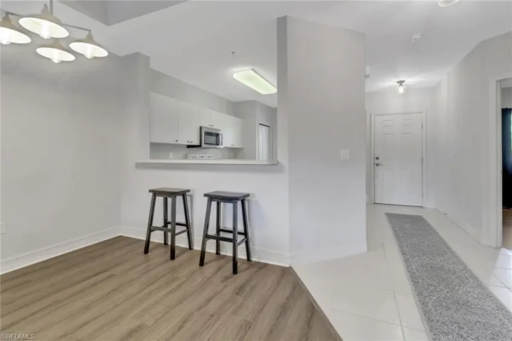 Kitchen with stainless steel microwave, white cabinets, a breakfast bar area, a chandelier, and light countertops