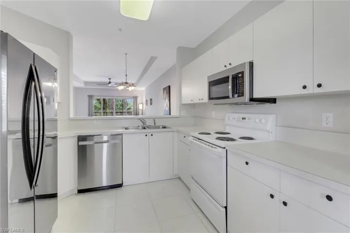 Kitchen featuring stainless steel appliances, light countertops, a sink, white cabinets, and ceiling fan