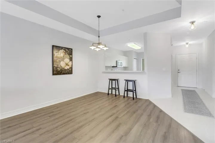 Living room featuring light wood finished floors, a chandelier, and baseboards